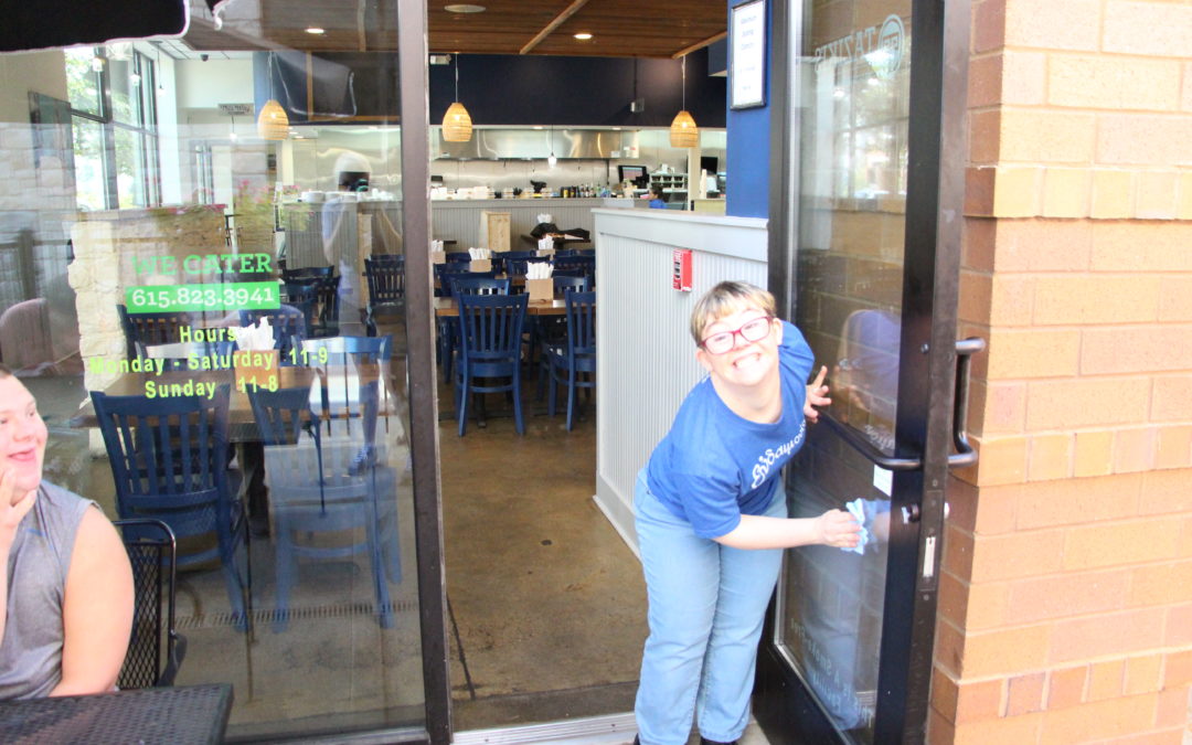 Woman cleaning glass door at restaurant